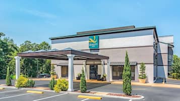 Welcome to Quality Inn, featuring a simple entrance with a canopy and potted plants.
