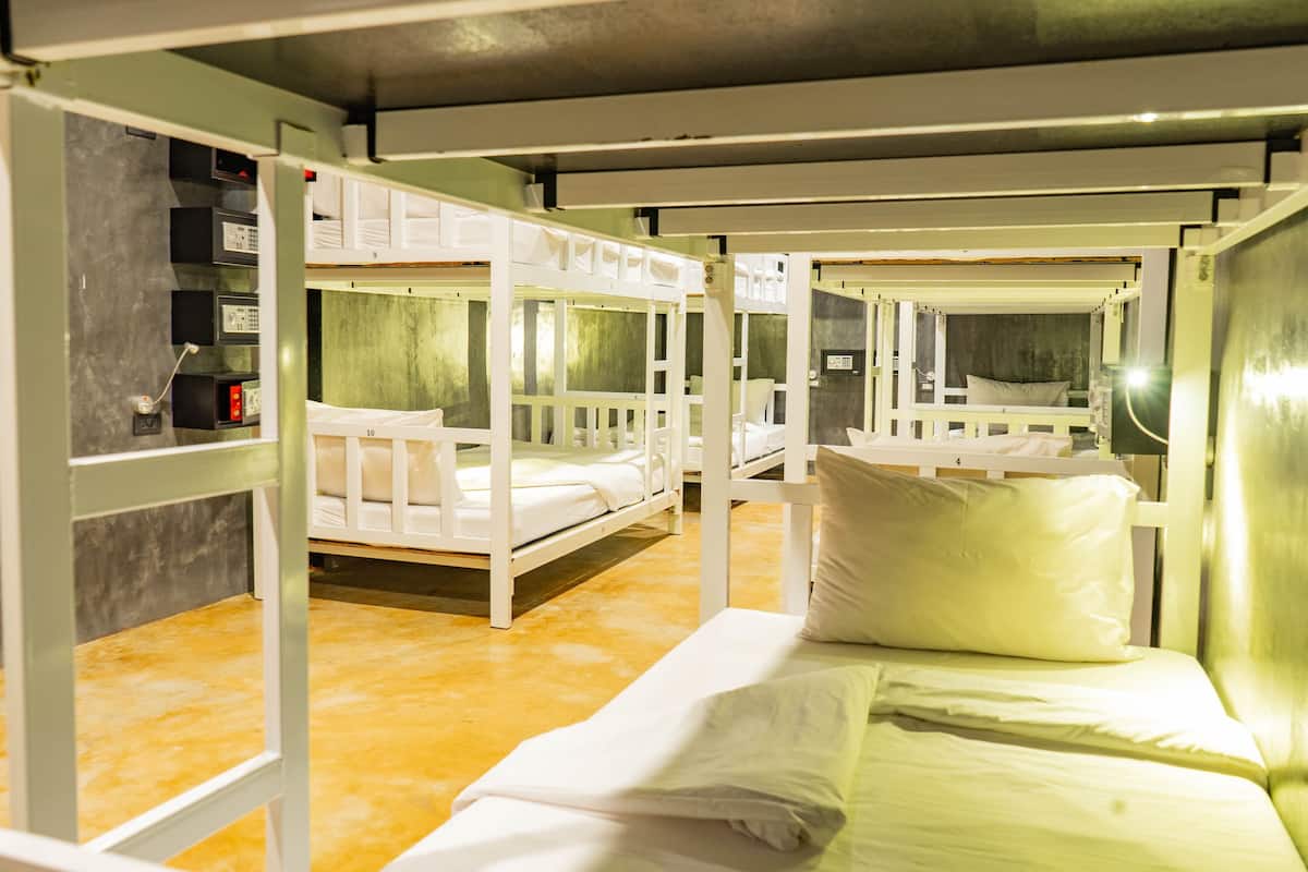 Une chambre de type dortoir, avec des lits superposés, un petit bureau et des étagères où sont rangés des effets personnels.