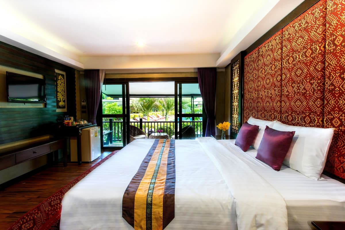 Une chambre d’hôtel avec un grand lit, un petit bureau, une télévision et un balcon donnant sur un paysage verdoyant.