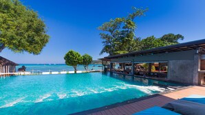 A poolside area with lounge chairs, a bar, and a view of the sea. - Ibiza House Phi Phi  (Ko Phi Phi)