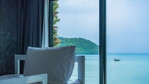 A room with a bed, a window, and a view of a calm sea and a distant island. - Ibiza House Phi Phi  (Ko Phi Phi)