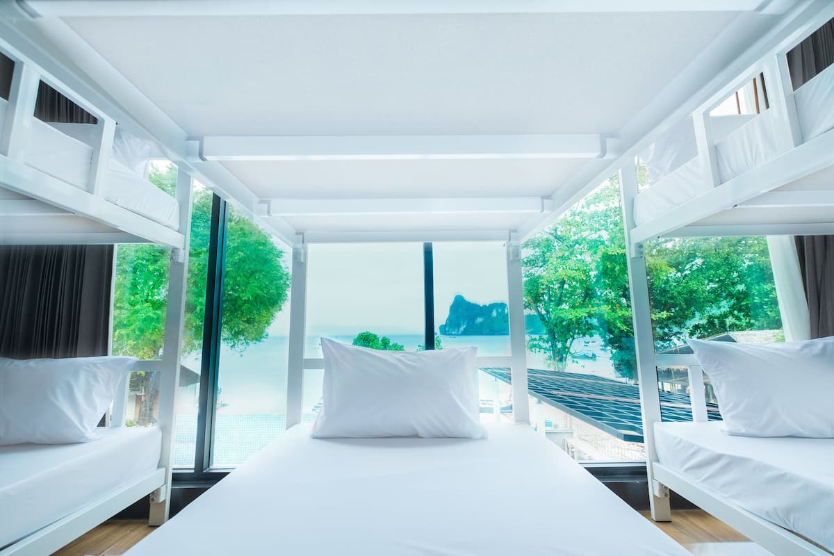Une chambre d’hôtel moderne avec un grand lit, du linge de lit blanc et une vue sur un paysage côtier.