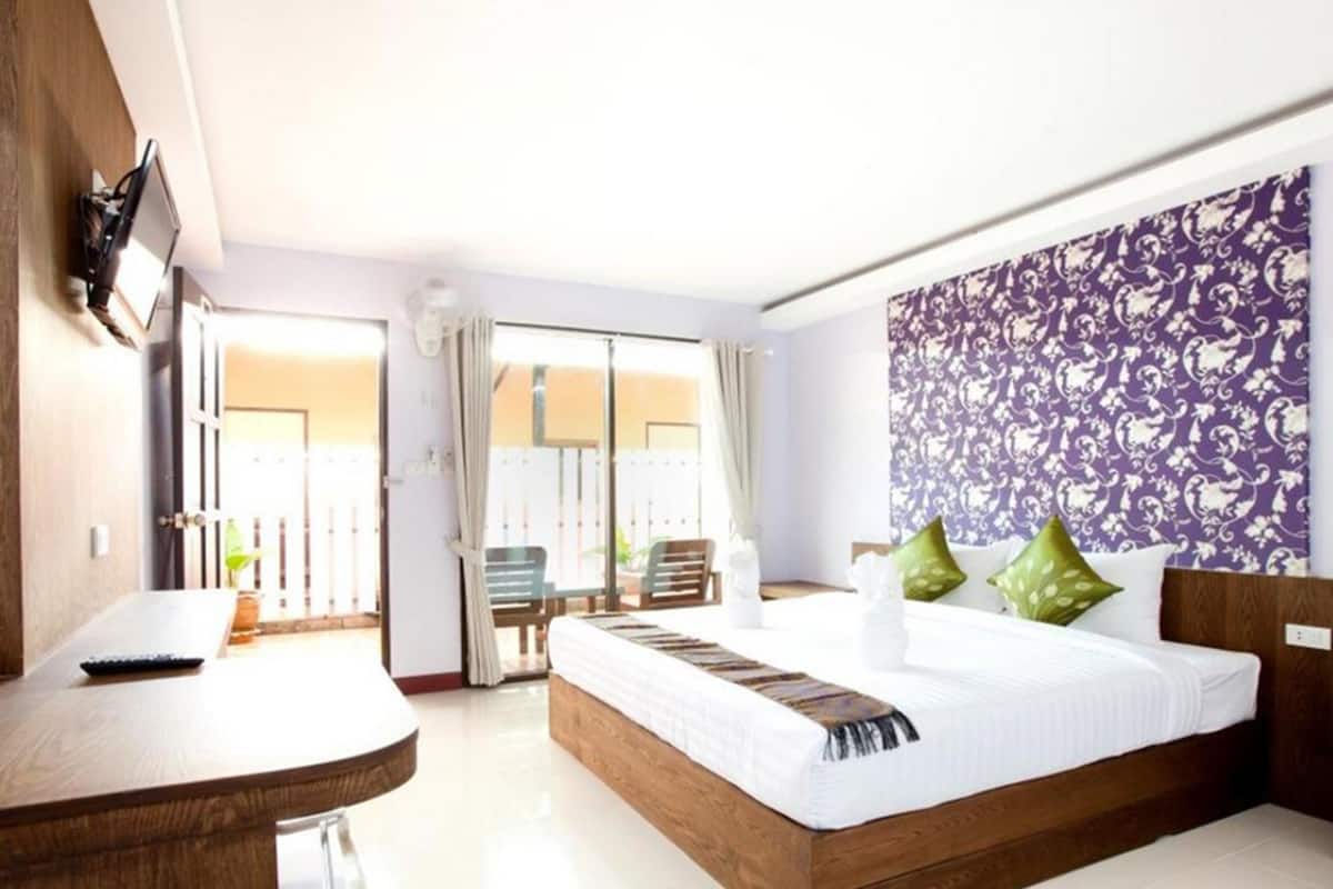 Une chambre d’hôtel avec un lit, un bureau, une télévision et un balcon équipé de chaises.