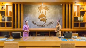 A reception desk with a logo of palm trees and a dolphin, and two staff members standing behind it. - Ibiza House Phi Phi  (Ko Phi Phi)