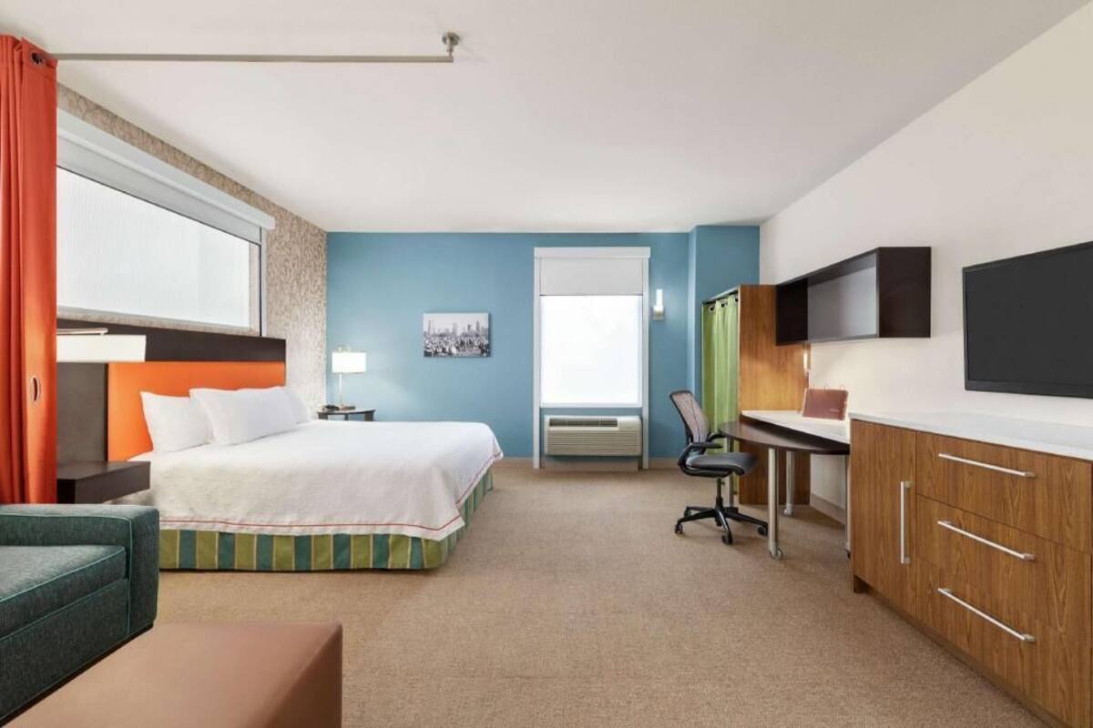 Een hotelkamer met een bed, bureau, stoel, televisie en een raam.