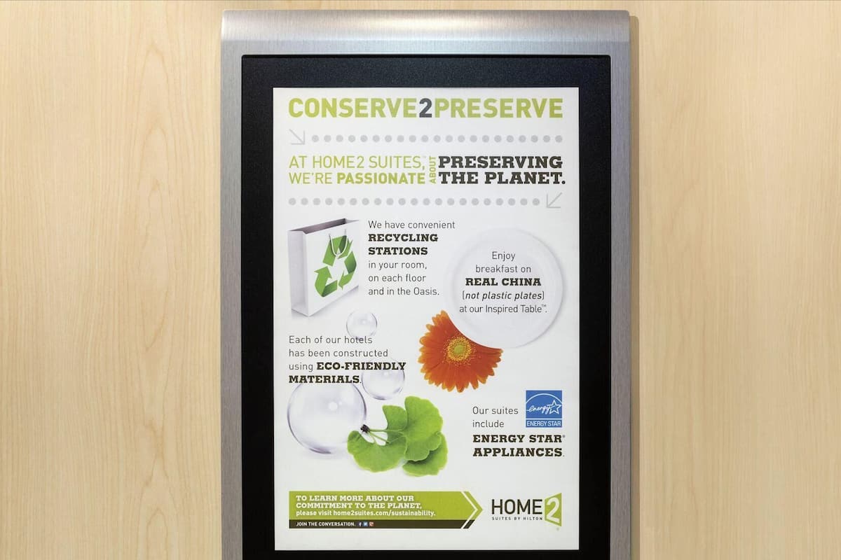 A sign detailing Home2Suites' sustainability efforts, including recycling stations, eco-friendly materials, and energy star appliances.