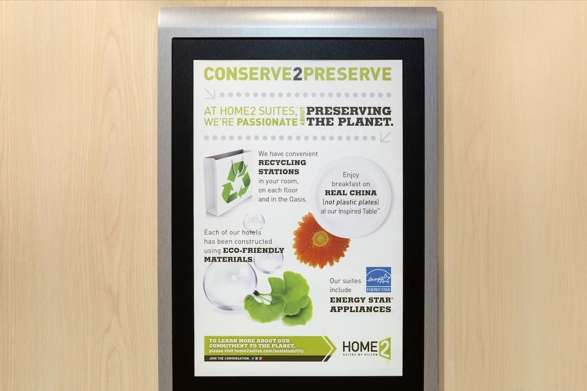 A sign detailing Home2Suites' sustainability efforts, including recycling stations, eco-friendly materials, and energy star appliances.
