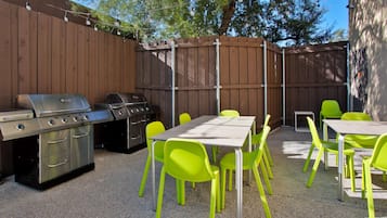 Une terrasse extérieure équipée d’un barbecue, d’une table et de chaises d’un vert vif.