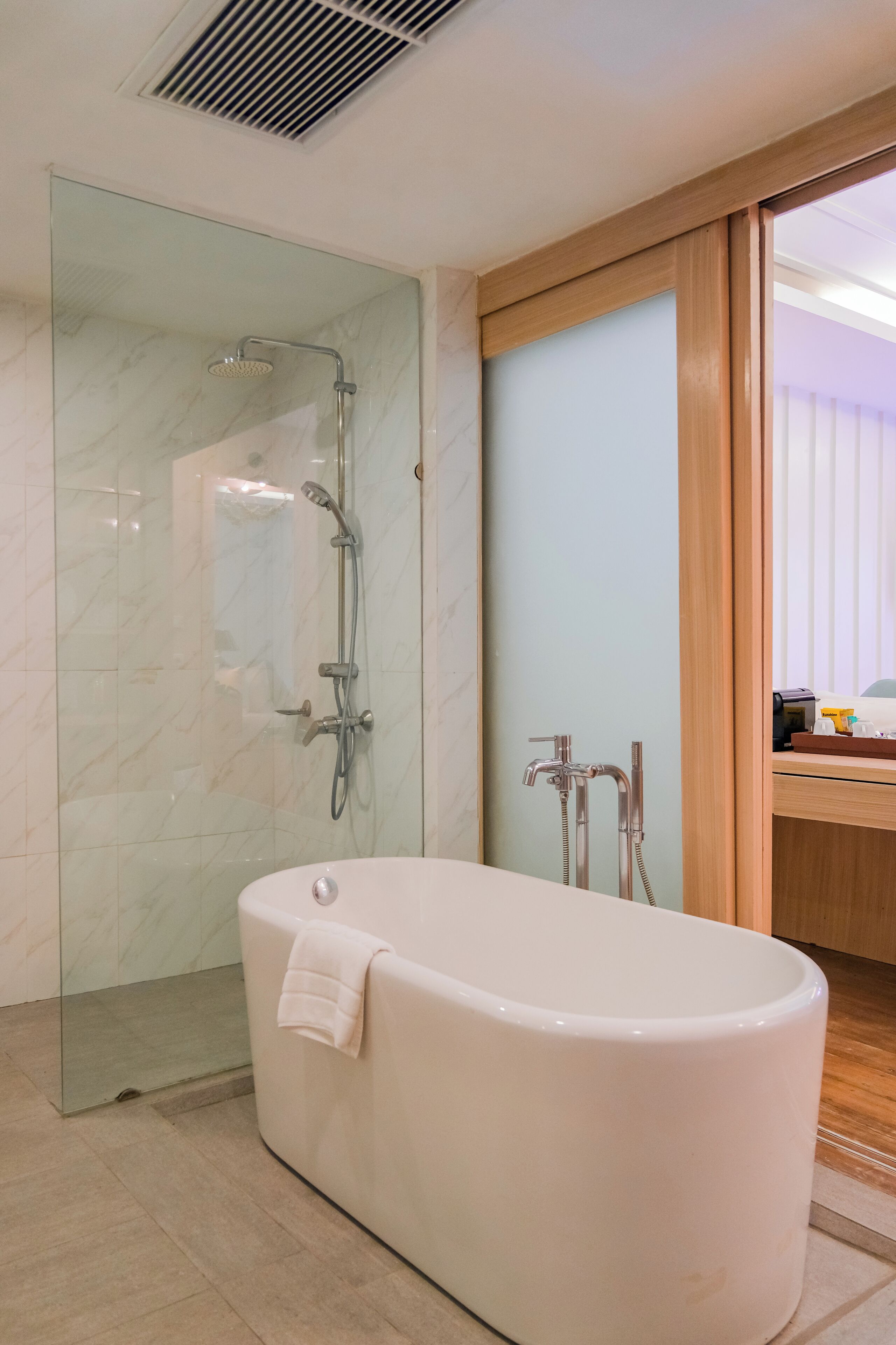 Ein modernes Badezimmer mit einer gläsernen Duschkabine, einer freistehenden Badewanne und einem hölzernen Waschtisch mit Spiegel.