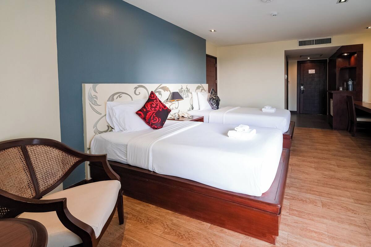 A hotel room with a large bed, a wooden chair, and a desk.