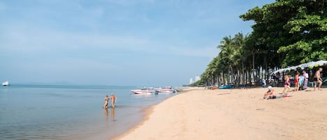 A beach with clear skies, calm water, and a few boats.
