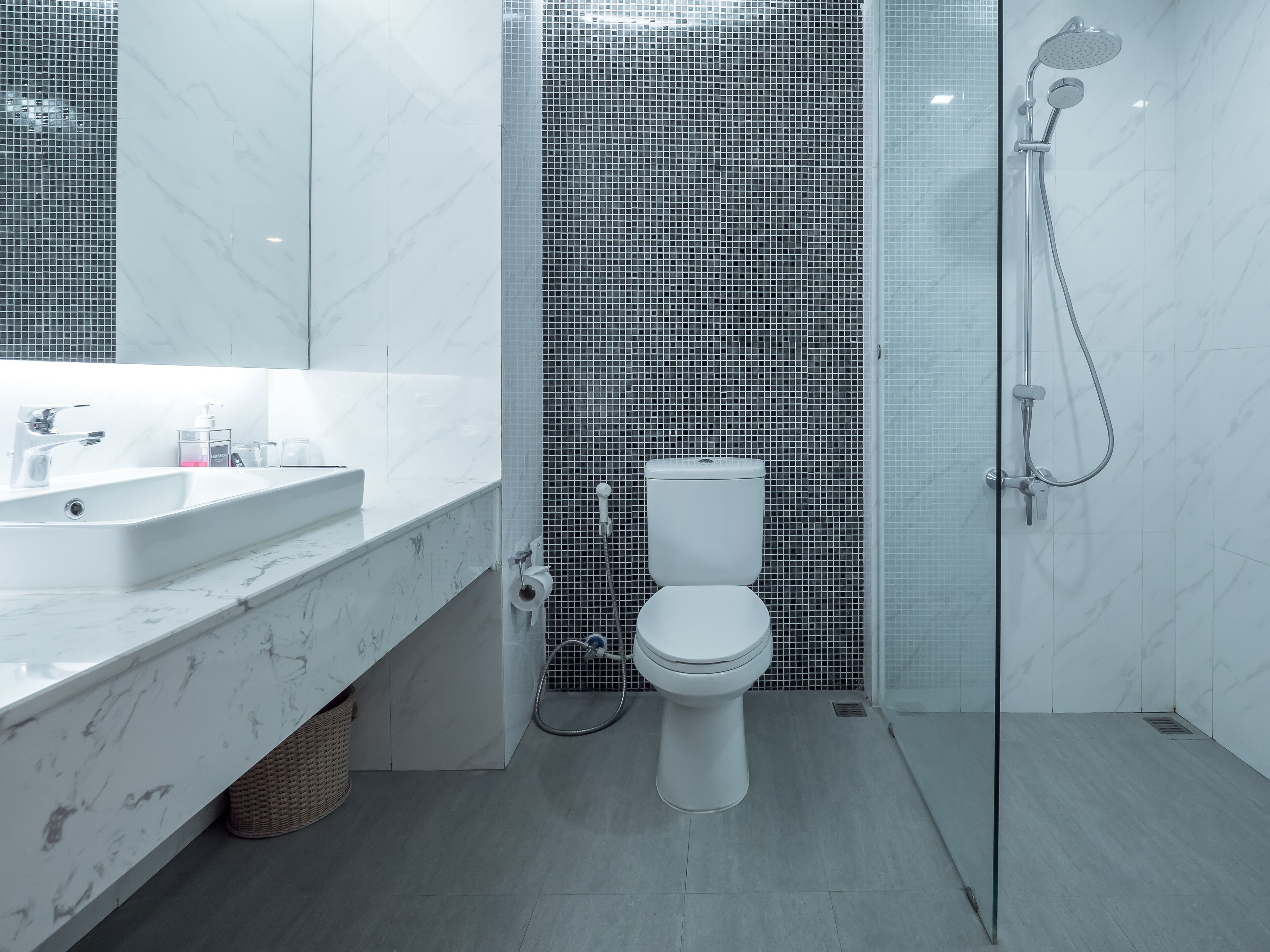 A modern bathroom with a white sink, toilet, and shower area.
