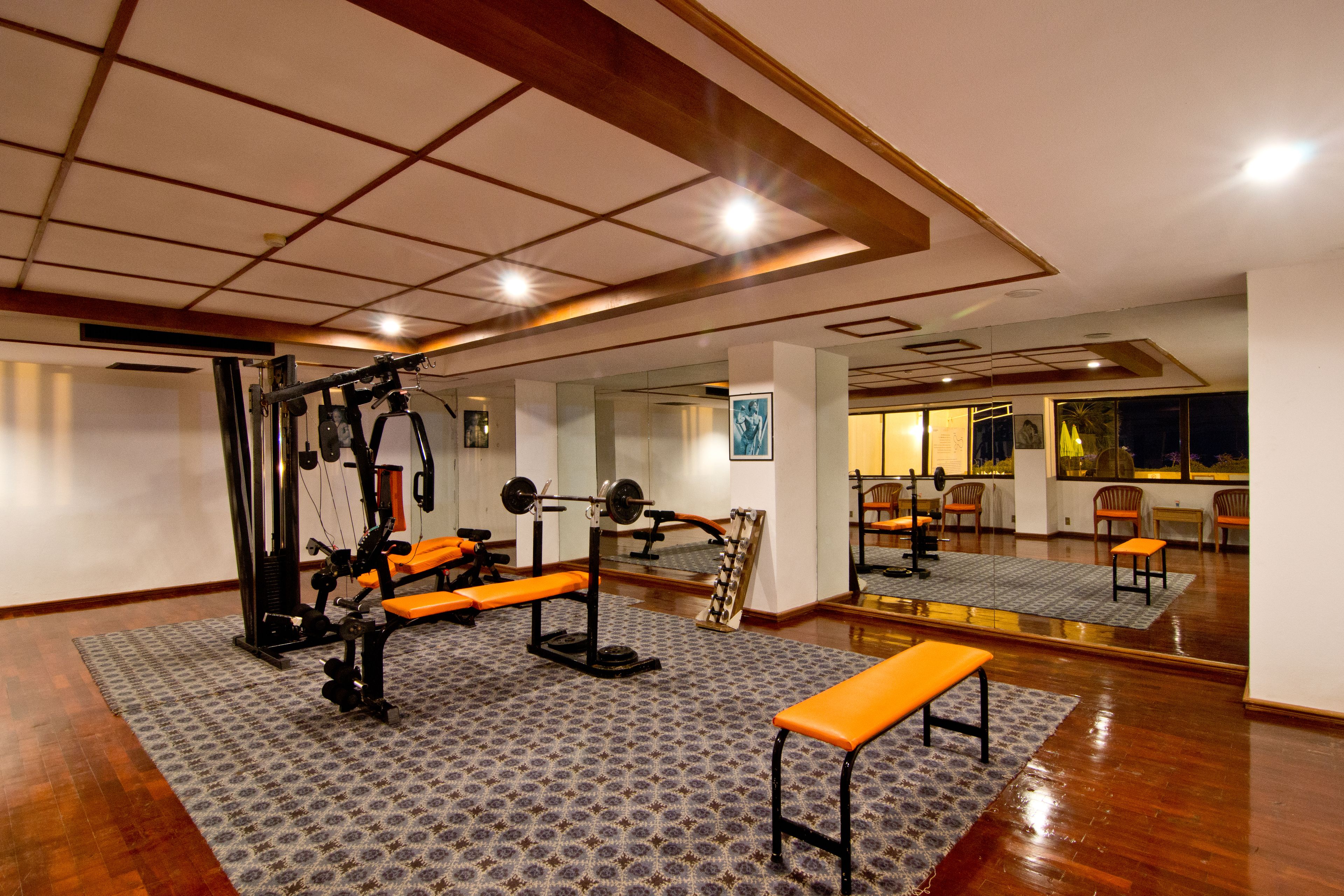 A gym with exercise equipment, benches, and a patterned rug.