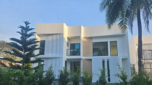 Un edificio moderno de dos pisos con techo plano, ventanas amplias y un balcón.