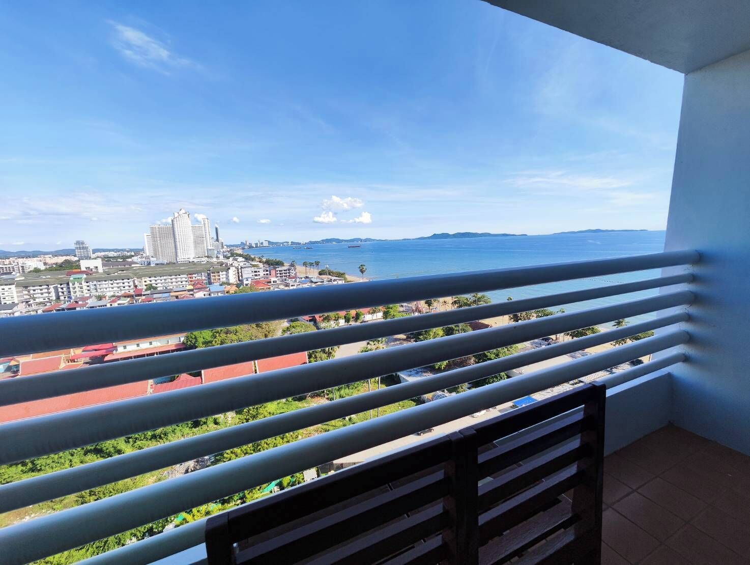 Un balcon offrant une vue sur un paysage urbain côtier, avec des bâtiments et une étendue d’eau.