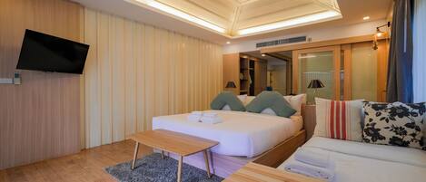 Una habitación de hotel moderna con cama, sofá, televisor de pantalla plana y un diseño de techo de madera.