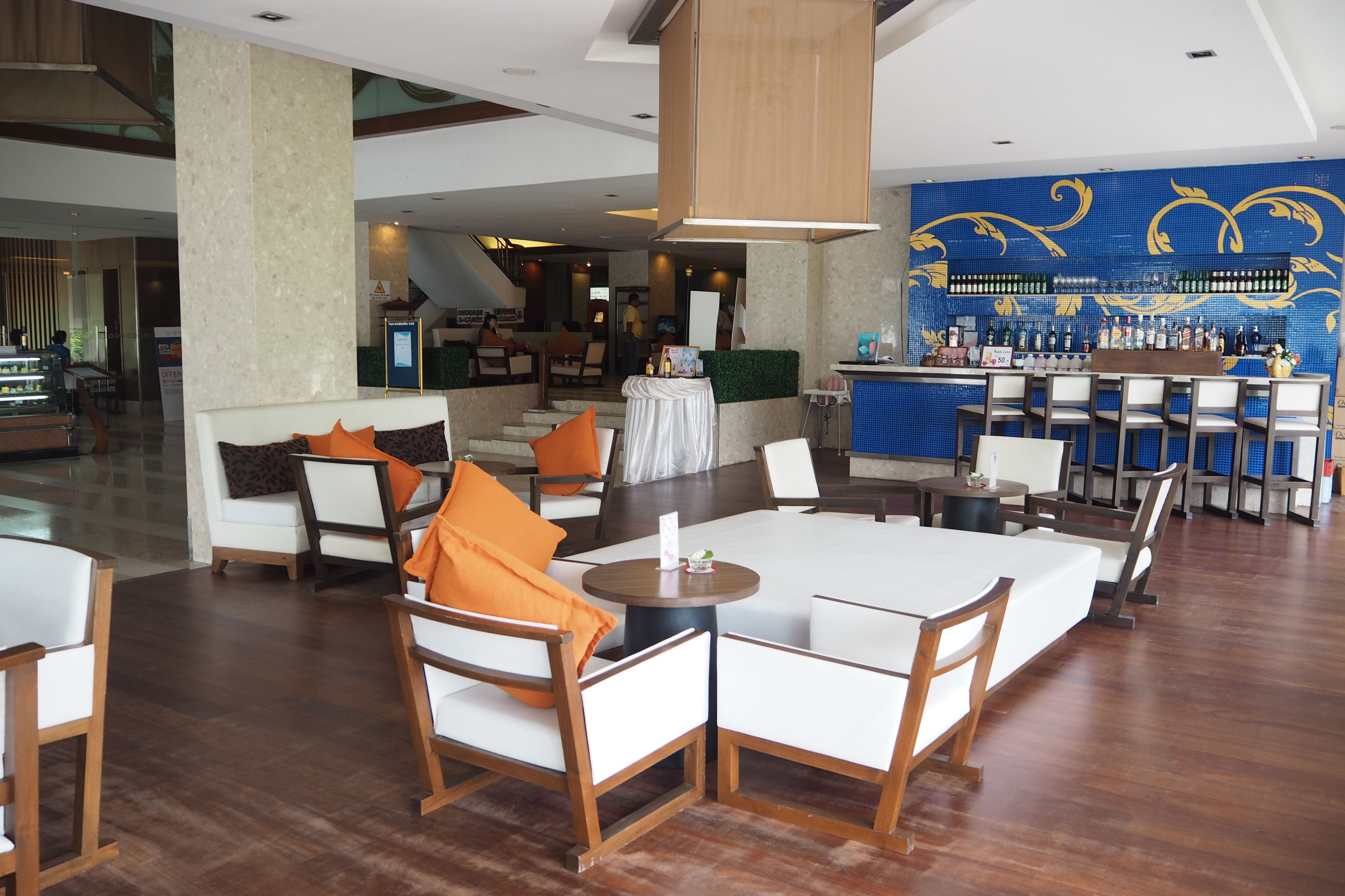 A modern hotel lobby with a bar area, seating arrangements, and a staircase in the background.