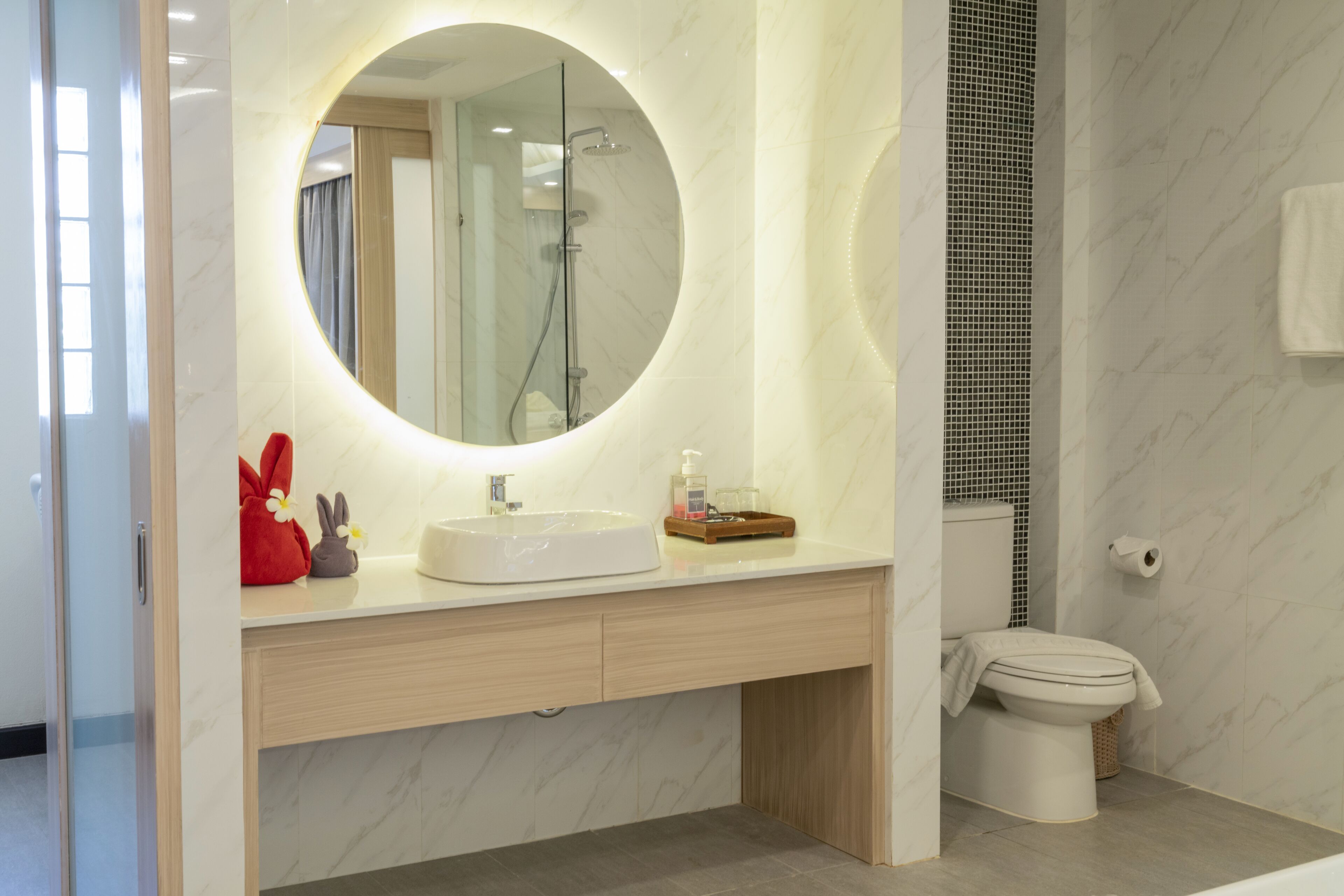 Een moderne badkamer met een ronde spiegel, een wastafel en een toilet.
