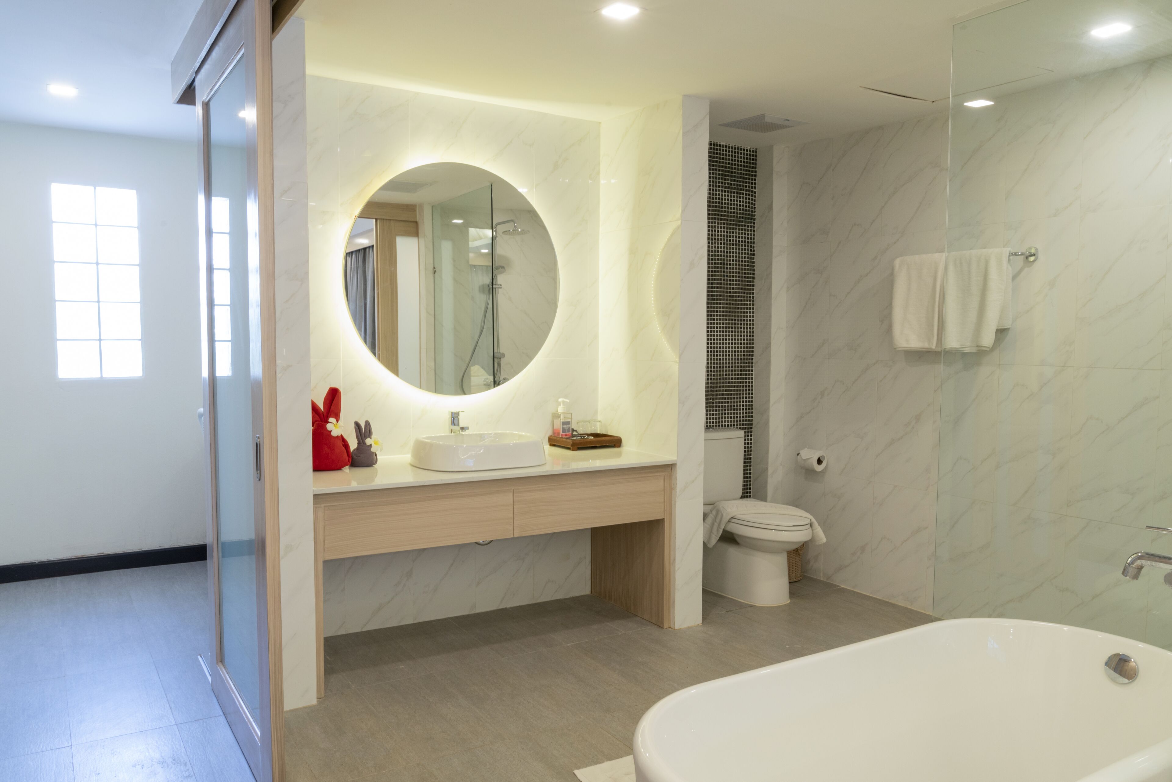 A modern bathroom with a large mirror, a bathtub, and a toilet.