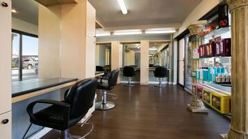 A salon with multiple black salon chairs, a counter, and a display of hair products.