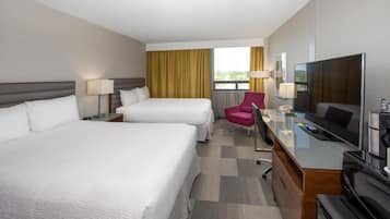 A hotel room with two beds, a desk with a TV, a chair, and a window with curtains.