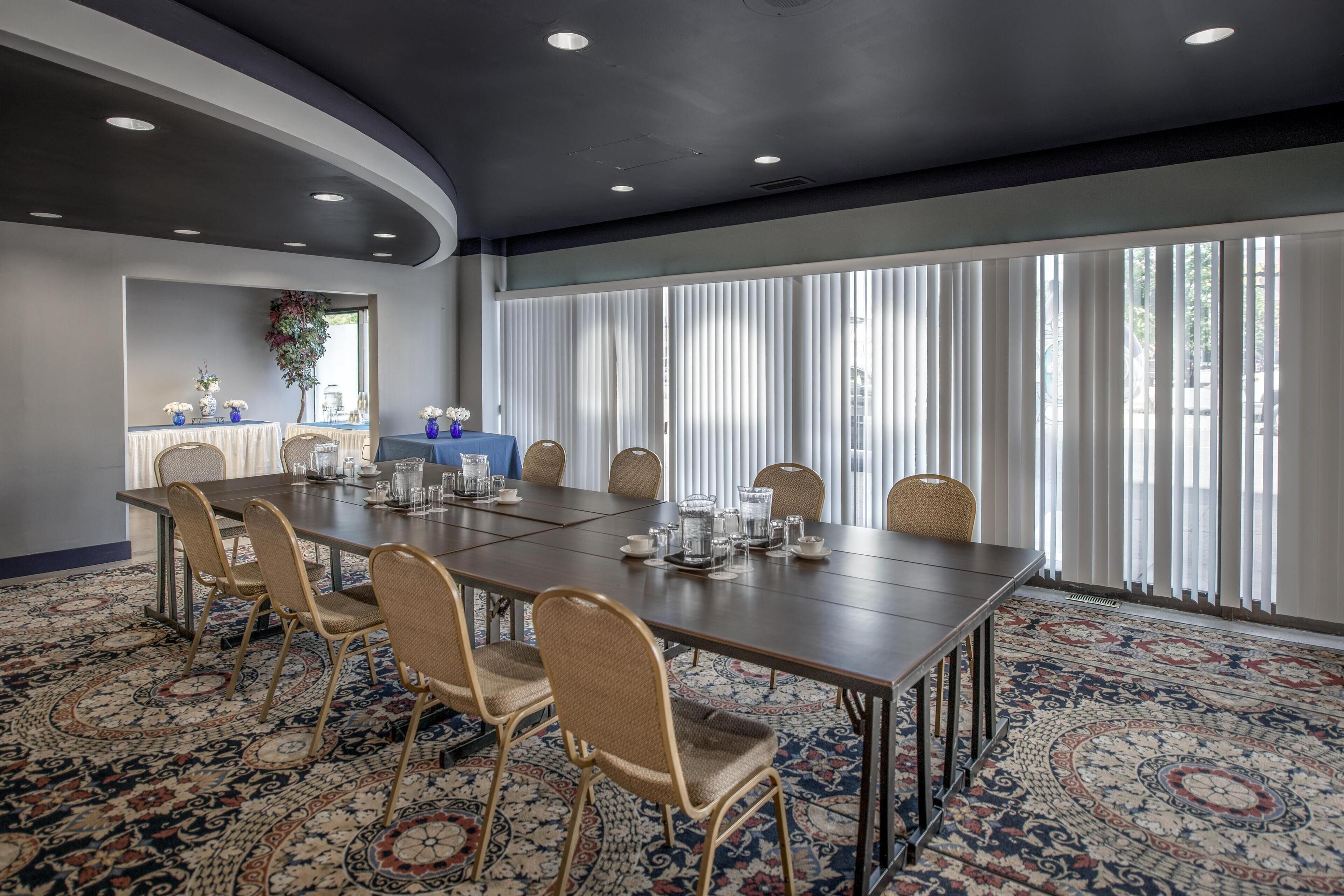 A conference room with a long table, chairs, and a patterned carpet.