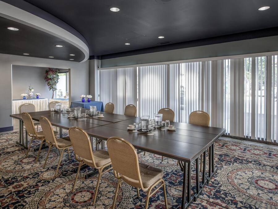 A conference room with a long table, chairs, and a patterned carpet.