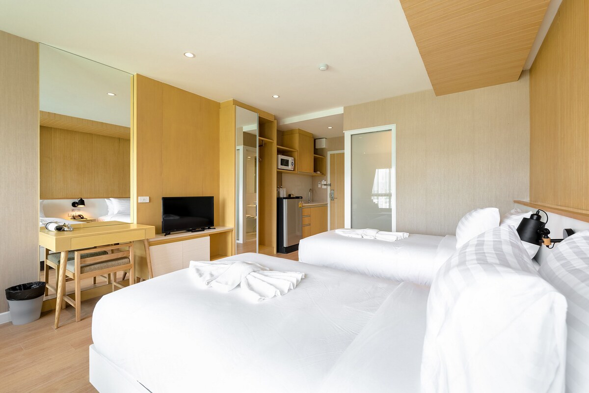 Een hotelkamer met een bed, een bureau met een televisie, een magnetron en een kleine kitchenette.