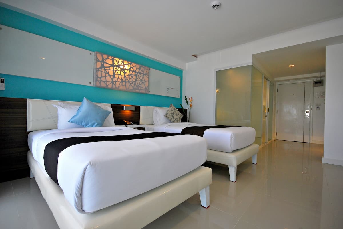 Een moderne hotelkamer met twee bedden, een grote spiegel en een decoratief kunstwerk aan de muur.