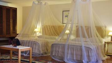 Two beds with canopy beds in a room.