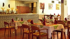 Interior de restaurante con paredes con diseño, varias mesas preparadas para comer y obras de arte en las paredes.