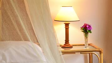 Un lit avec un oreiller blanc, une lampe de chevet et un vase de fleurs posé sur une table de chevet.
