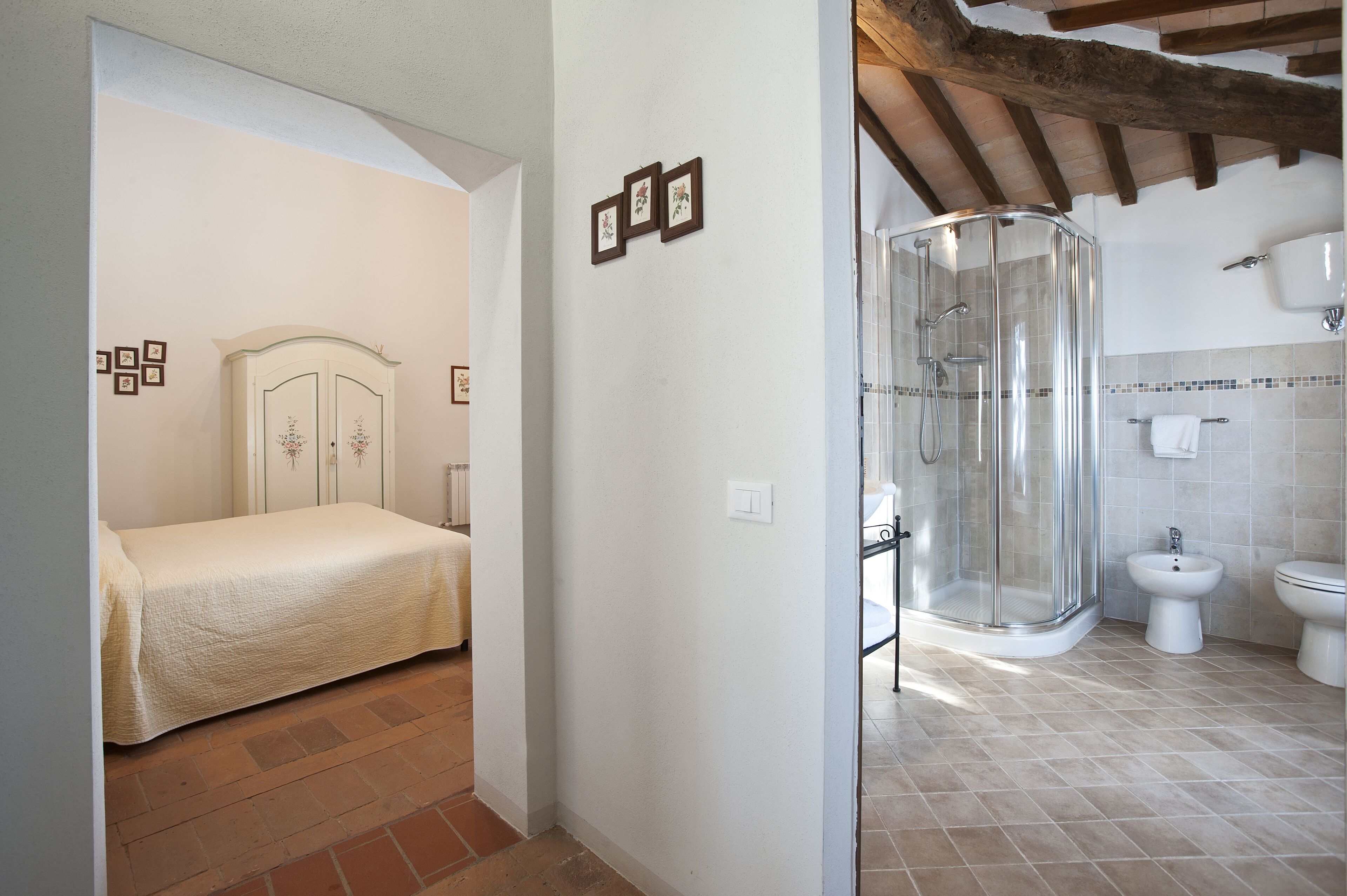 Une chambre avec un lit et une armoire, une salle de bain avec une douche, des toilettes et un bidet.