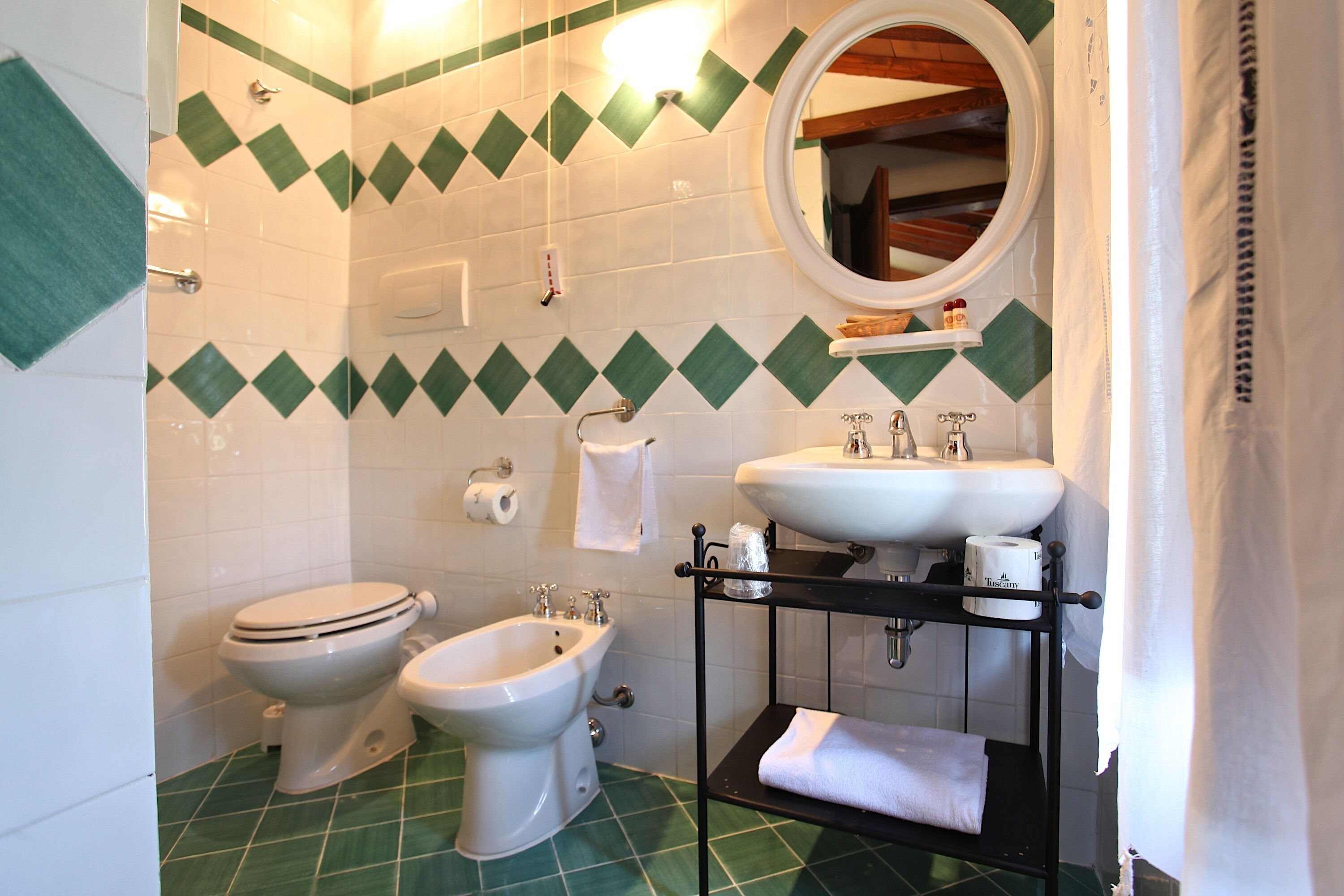 Un baño con inodoro, bidé, lavabo y toallero.