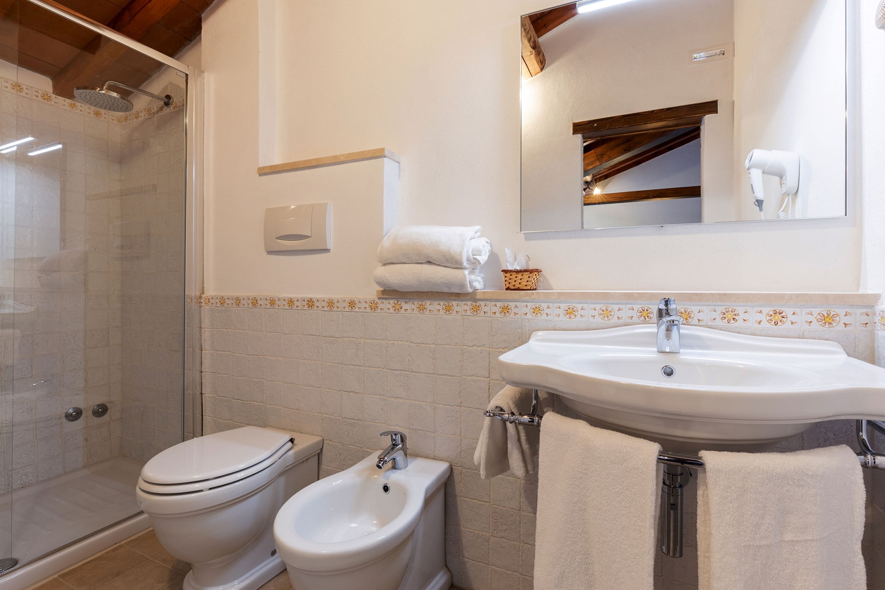 Un baño con ducha, inodoro, bidé, lavabo y espejo.