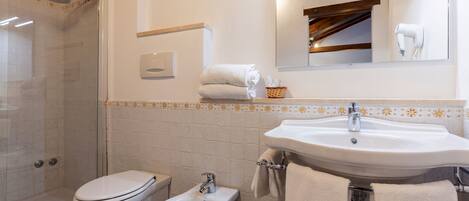 Un baño con ducha, inodoro, bidé, lavabo y espejo.