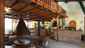 A rustic interior with a brick fireplace, wooden beams, and a bar area. - Fattoria Pieve a Salti (Montalcino)