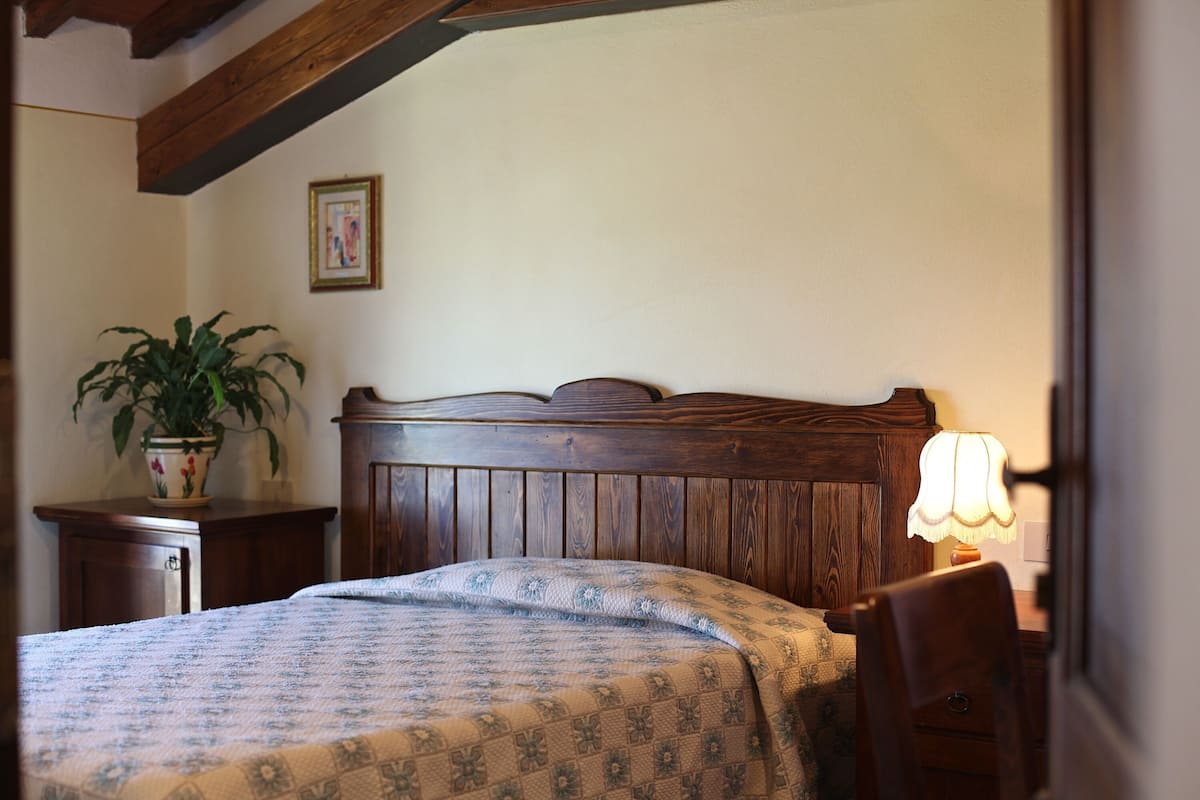Une chambre à coucher avec une tête de lit en bois, une table de chevet avec une lampe et une plante en pot.