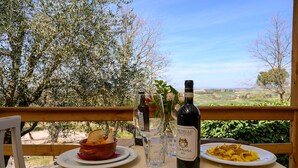 A table with a bottle of Brunello di Montalcino wine, a plate of food, and a bowl of bread. - Fattoria Pieve a Salti (Montalcino)