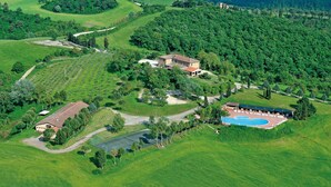 An aerial view of a property with a main building, a swimming pool, and surrounding green fields. - Fattoria Pieve a Salti (Montalcino)