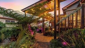 Un espace extérieur abrité, doté d’un chemin en briques, de structures en bois et de diverses plantes.