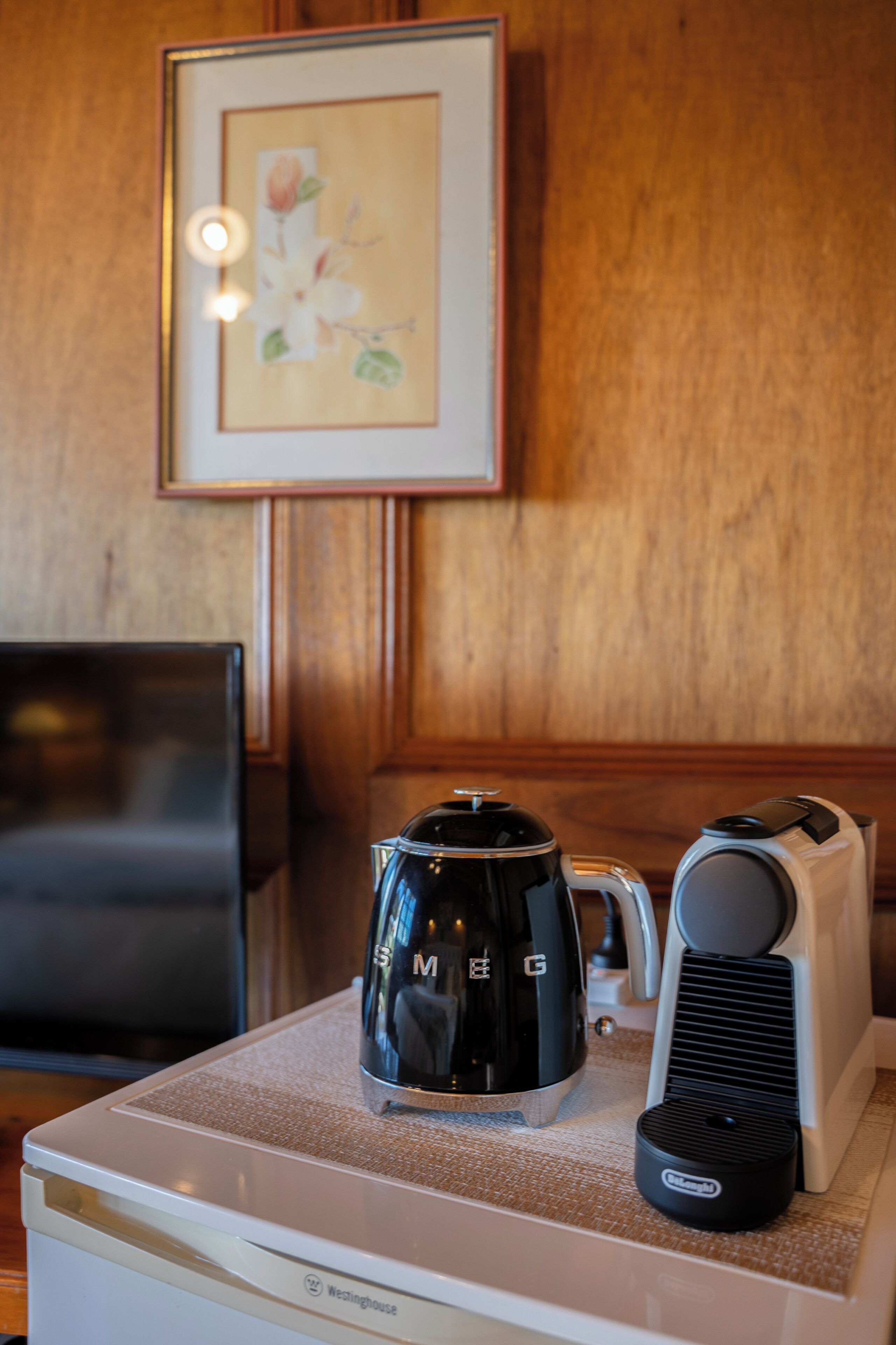 Una kitchenette con cafetera, tostadora y un cuadro en la pared.
