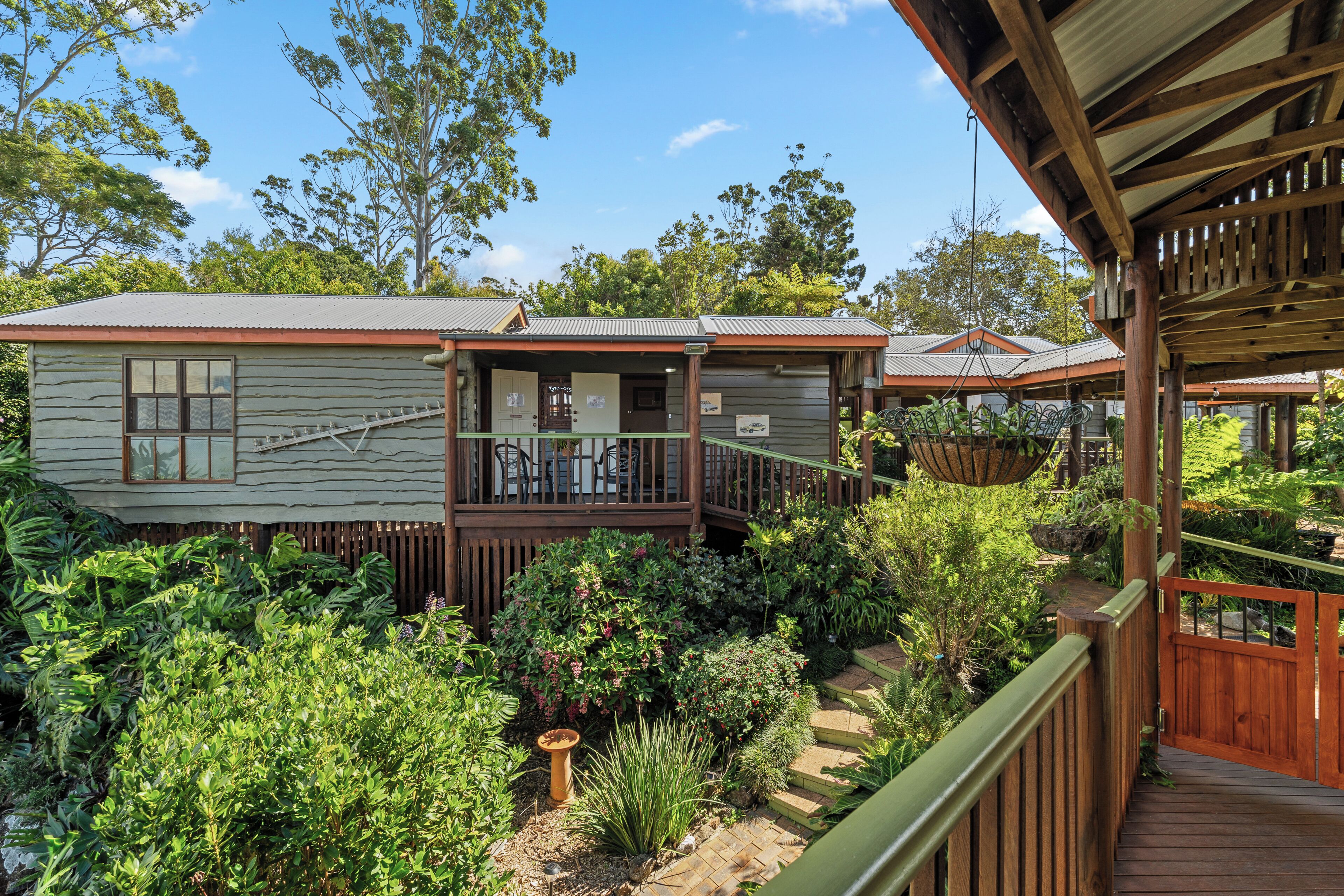 A wooden deck with a view of a building surrounded by lush greenery.