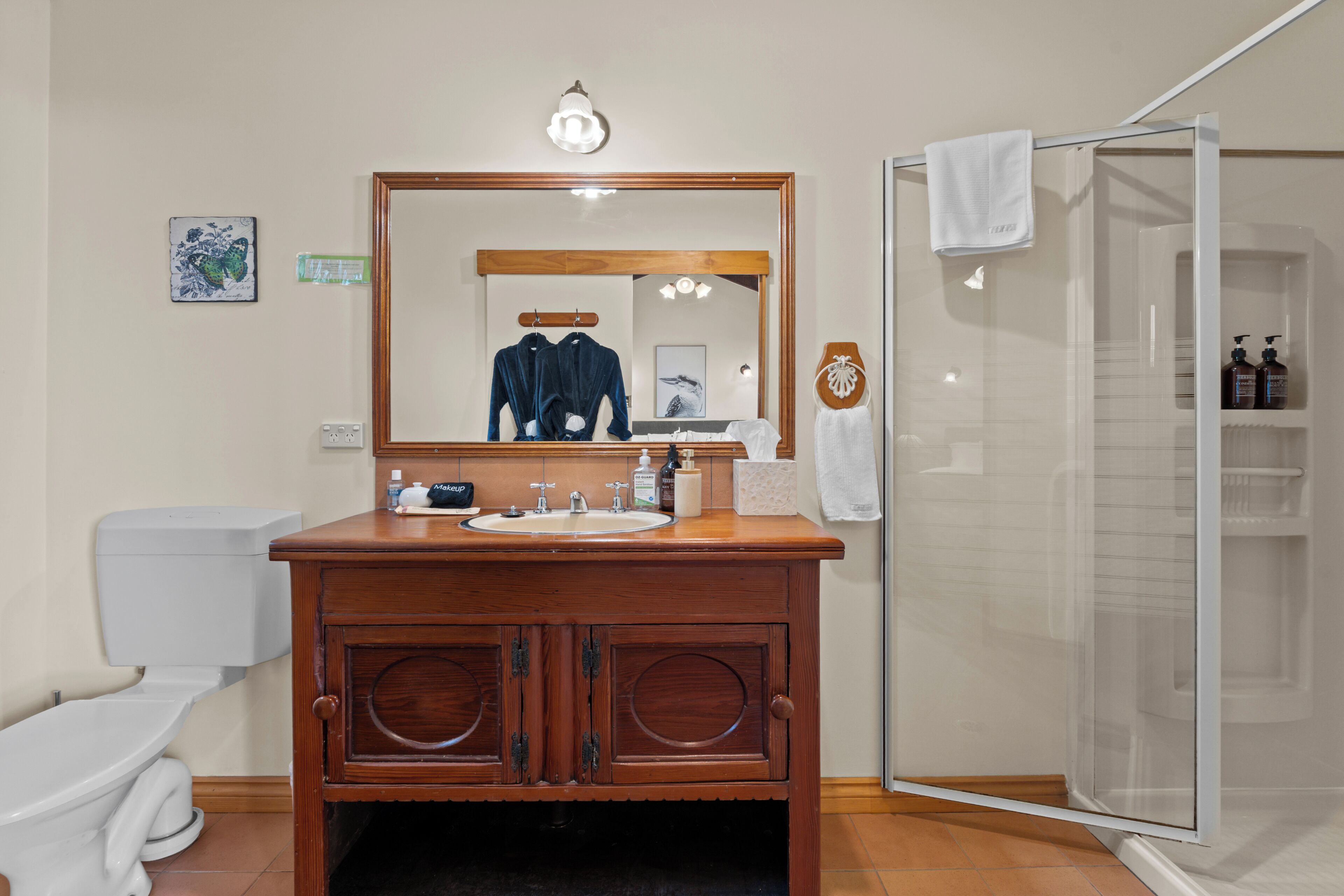 A bathroom with a wooden vanity, a large mirror, a toilet, and a shower enclosure.