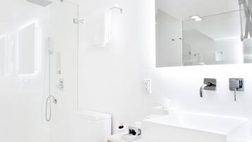 A modern bathroom with a white sink, mirror, and toilet.