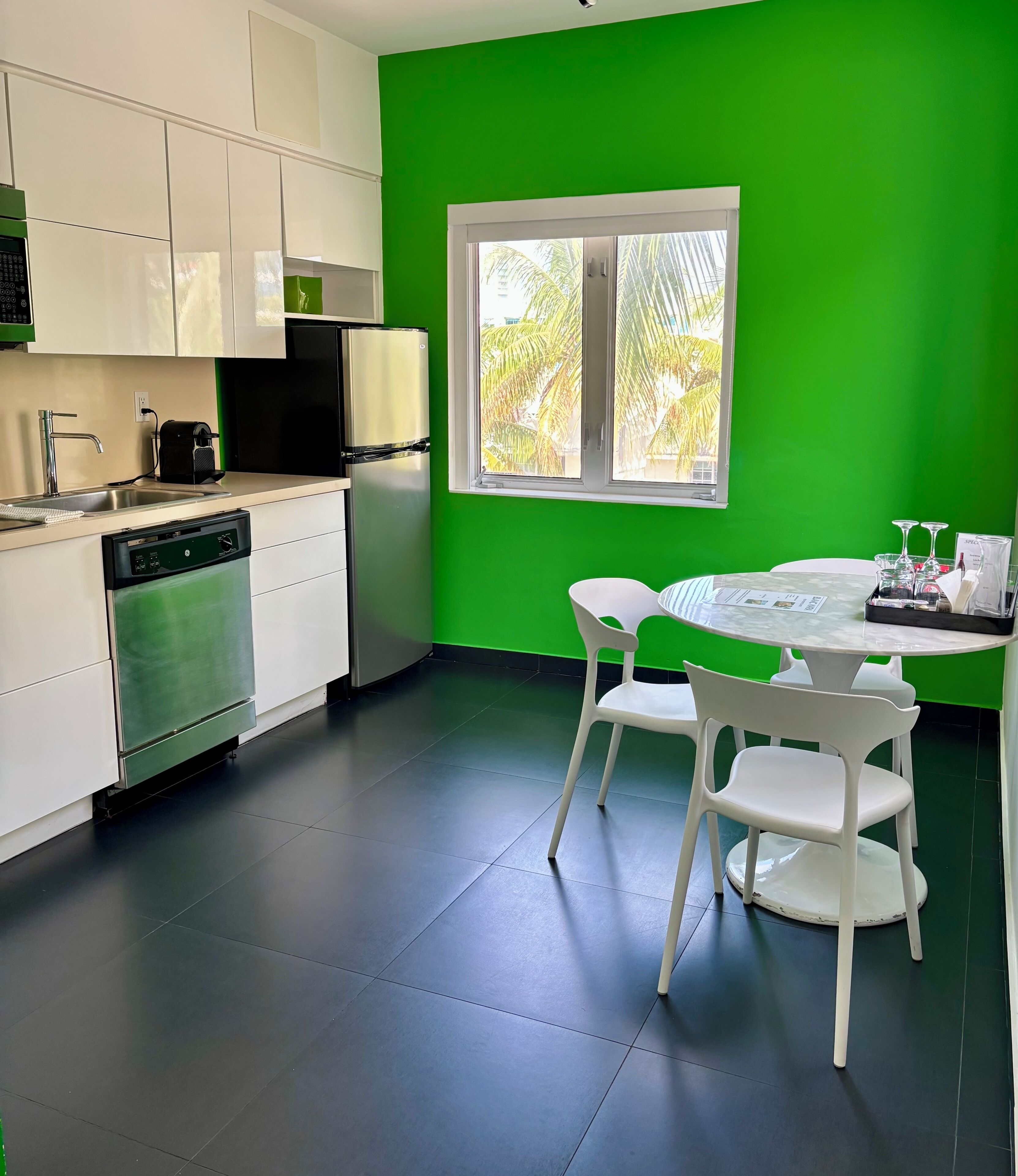 Een moderne keuken met witte kasten, een vaatwasser en een groene wand.