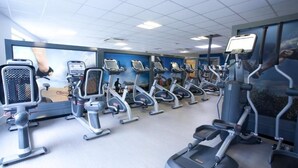 Kuntosali, jossa on useita juoksumattoja ja crosstrainereita, jotka on järjestetty riveihin.