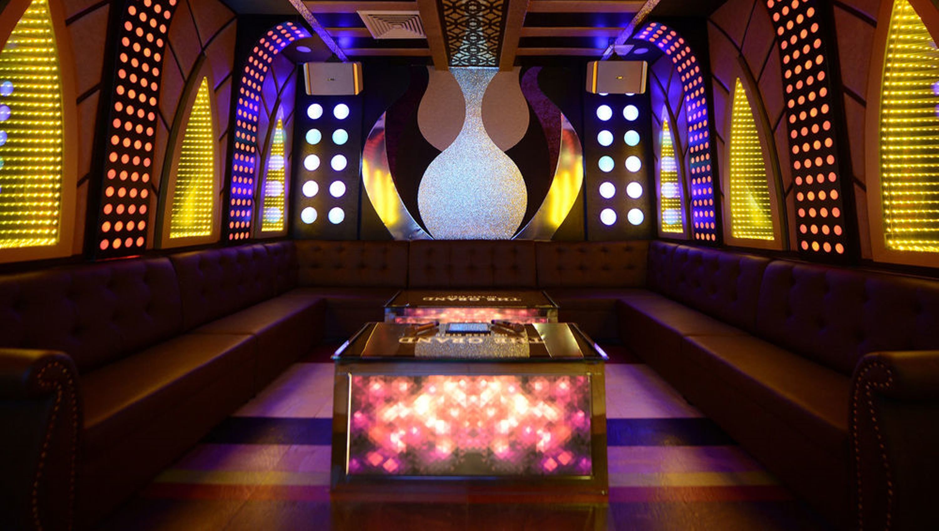 A modern lounge area with a central table, cushioned seating, and decorative lighting.