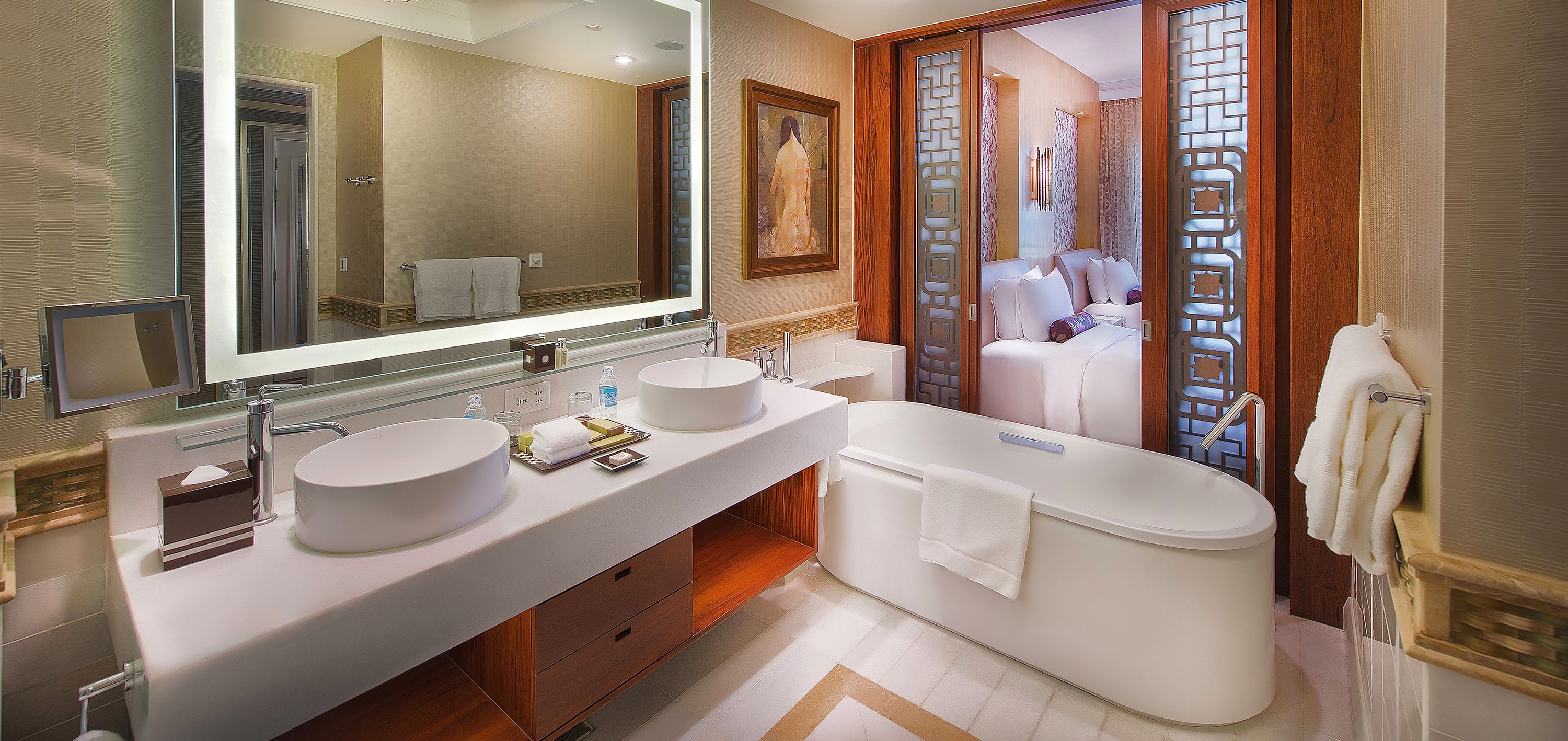 Un baño moderno con un espejo grande, dos lavamanos, una bañera y un vestidor.