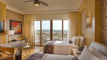 A hotel room with a balcony, a bed, a sofa, a desk, and a TV.